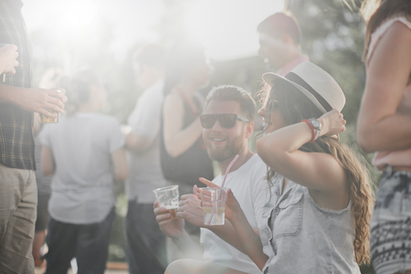 Couple sitting and drinking alcohol at outdoor partyの写真素材