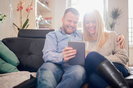 Couple using tablet while sitting on sofa at home.の写真素材