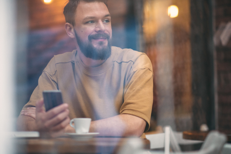 Young man sitting in cafe and using smart phone.の写真素材