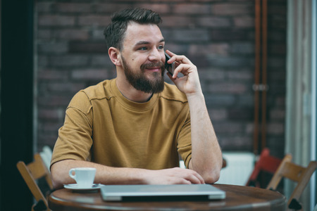 Young man sitting in cafe and using smart phone.の写真素材