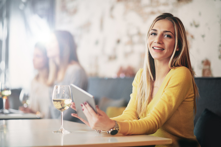 Young caucasian woman using tablet while sitting in cafe and drinking coffee.の写真素材