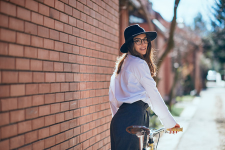Woman walking down the street and holding the bicycle.の写真素材