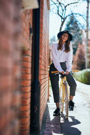 Woman posing on the bicycle. Next to her brick wall.の写真素材