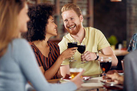 Friends making a toast while sitting in restaurant. Multi-ethnic group.の写真素材