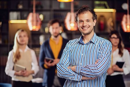 Young attractive arab businessman standing at restaurant with arms crossed. In background his...