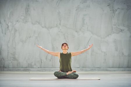 Beutiful woman sitting on the mat in lotus posture.の写真素材