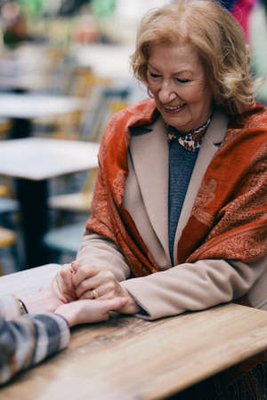 Grandmother with her granddaughter is sitting outside of the cafe. She is happy to spend time with her granddaughter.の写真素材