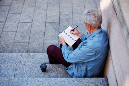 Top view of a senior man sitting outside and writing to do list.の写真素材