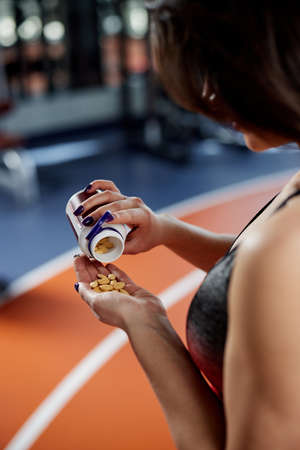 Close up of a sportswoman's hand taking supplements and pills in a gym.の写真素材