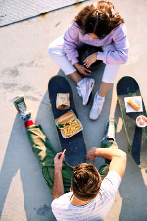 Top view on teenagers eating fast food on their skateboards. Selective focus on a teenage boy's head...