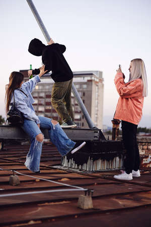 Teenagers hanging on rooftop and drinking beer.の写真素材