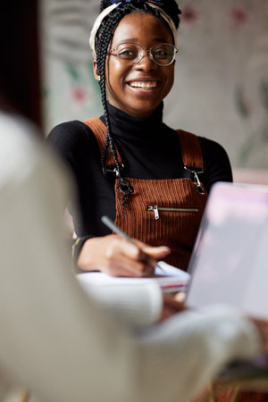 Two multicultural female students sitting in cafeteria and study for exam.