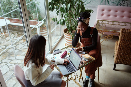 Two multicultural female students sitting in a cafe and studying for an exam. The lifestyle of a student.の写真素材