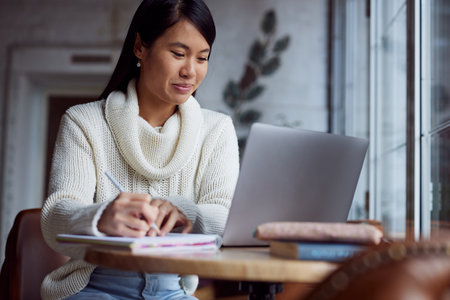 An asian female student sitting in cafeteria and studies for a test.の写真素材
