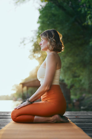 A calm woman sits in a diamond yoga pose and practices breathing exercises.の写真素材