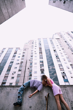Teenage couple kissing in urban exterior surrounded by buildings.の写真素材