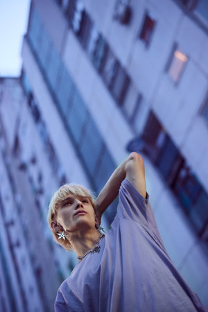 A teenage boy is posing in the urban exterior surrounded by buildings.の写真素材