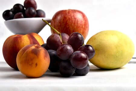 Seasonal fruits in which they are found; peach, mango, grape, apple, diffuse white backgroundの写真素材