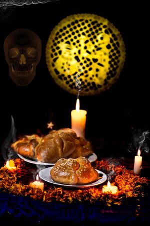 pan de muerto, placed on white plates, adorned with cempasuchil petals and burning candles around it. Diffuse background with confetti, traditional Mexicanの写真素材