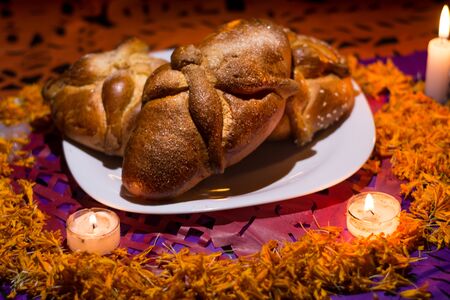 Bread of dead on chopped paper and lighted candles with grapefruit petals, dark background, Day of the dead.の写真素材