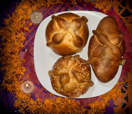 Bread of the dead on confetti and lighted candles with cempasuchil petals, Day of the Dead, Dark backgroundの写真素材