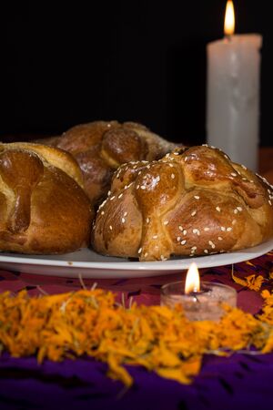 Bread of the dead on confetti and lighted candles with cempasuchil petals, Day of the Dead, Dark backgroundの写真素材