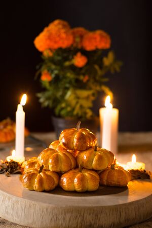 Pumpkin bread, placed in a pyramid, around a candle and cempazuchitl flower, next to a natural pumpkin. In the background pumpkin bread and a pot of cempazuchitl flowersの写真素材