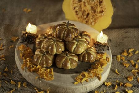 Pumpkin bread, placed in a pyramid, around a candle and cempazuchitl flower, next to a natural pumpkin.の写真素材