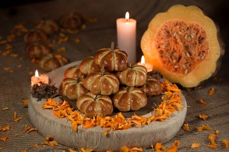 Pumpkin bread, placed in pyramid, around a candle and cempazuchitl flower, next to a natural pumpkin, in the background diffuse pumpkin bread.の写真素材