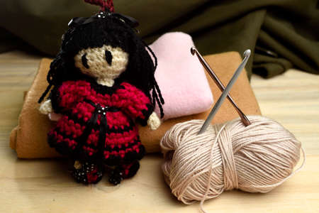 doll made with yarn, around it sewing needles, yarn and fabric, placed on Woodの写真素材