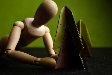 Wooden Human Art Mannequin placed in front of a tree made of paper and painted with acrylics, green diffuse background.の写真素材