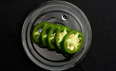 JalapeÃ±o pepper cut into slices and placed on a transparent glass plateの写真素材
