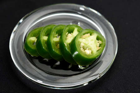 JalapeÃ±o pepper cut into slices and placed on a transparent glass plateの写真素材