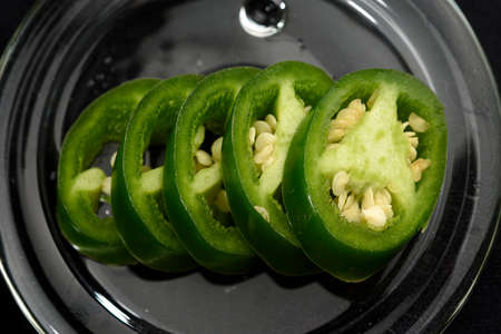 JalapeÃ±o pepper cut into slices and placed on a transparent glass plateの写真素材