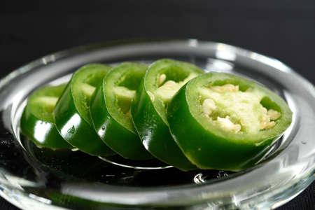 JalapeÃ±o pepper cut into slices and placed on a transparent glass plateの写真素材