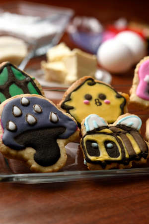 Cookies made with butter and decorated with various figures, in the background in diffuse raw materials for their preparation, mentioning butter, flour, eggs and sugar.の写真素材