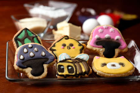 Cookies made with butter and decorated with various figures, in the background in diffuse raw materials for their preparation, mentioning butter, flour, eggs and sugar.の写真素材