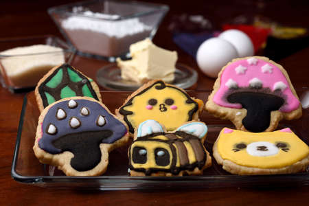 Cookies made with butter and decorated with various figures, in the background in diffuse raw materials for their preparation, mentioning butter, flour, eggs and sugar.の写真素材