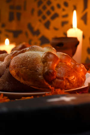 Traditional and sugary bread of the dead, around it marigold flowers, cardboard coffin, lighted candles, diffused confetti background.の写真素材