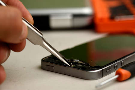 cell phone under repair, screwdriver on the side, back of a laptop and box of screwdriversの写真素材