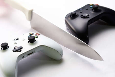 Contrast black and white wireless controls separated by a kitchen knife, placed on a white...