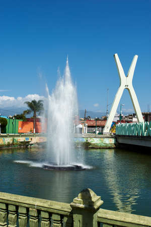 Lake with water fountain in the center, next to the bridgeの写真素材