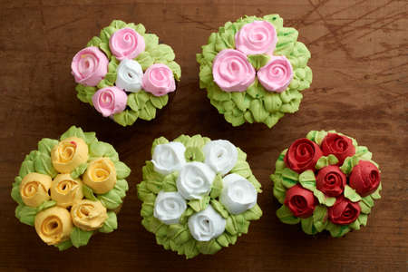 cupcakes decorated with rose design chantilly, placed on a wooden baseの写真素材