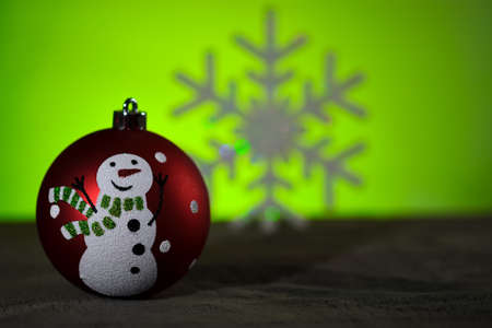 Christmas sphere with a design of a snowman with a tie, in the background an artificial snowflakeの写真素材