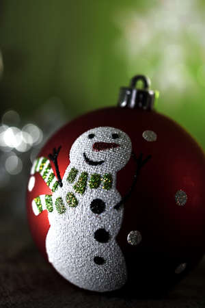 Christmas sphere with a design of a snowman with a tie, in the background an artificial snowflakeの写真素材