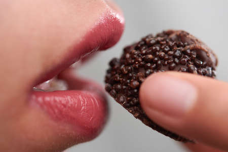girl eating a chocolate with a texture, closeup of the mouthの写真素材