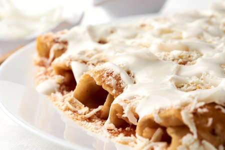 Enchiladas with cheese and cream, Veracruz style. a hand is shown pouring cream onto the enchiladas. mexican grastononomyの写真素材