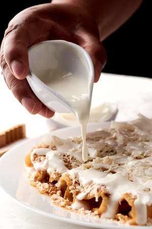 Enchiladas with cheese and cream, Veracruz style. a hand is shown pouring cream onto the enchiladas. mexican grastononomyの写真素材