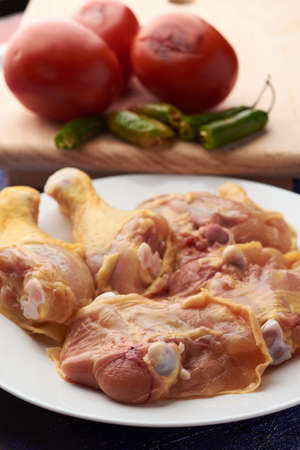 Chicken pieces placed on a plate, garnish tomatoes and chili peppers placed on a wood.の写真素材