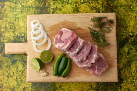 Pork for tacos, knuckle, around there are serrano peppers, garlic, onion, oregano, thyme and bay leaves, lemon, placed on a wooden base.の写真素材
